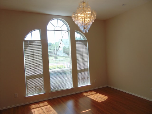 unfurnished room with an inviting chandelier and wood-type flooring