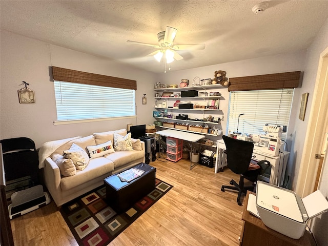 office space featuring a textured ceiling, light wood-type flooring, and ceiling fan