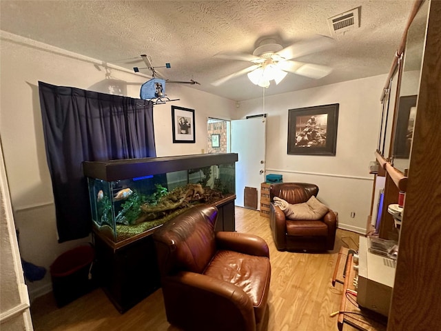 bedroom featuring a ceiling fan, a textured ceiling, visible vents, and light wood-type flooring