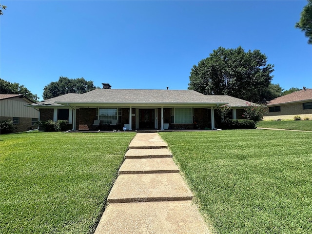 ranch-style home featuring a front lawn, brick siding, and a chimney