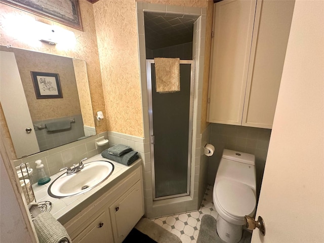 full bath with a shower stall, toilet, vanity, tile walls, and wainscoting