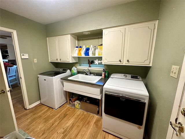 laundry area with a sink, cabinet space, light wood finished floors, baseboards, and independent washer and dryer