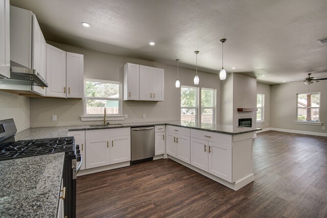 kitchen featuring appliances with stainless steel finishes, sink, white cabinets, kitchen peninsula, and stone countertops