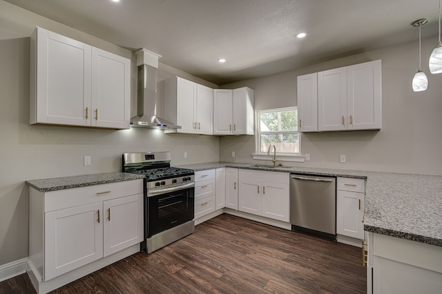 kitchen featuring appliances with stainless steel finishes, wall chimney exhaust hood, white cabinetry, dark hardwood / wood-style flooring, and sink