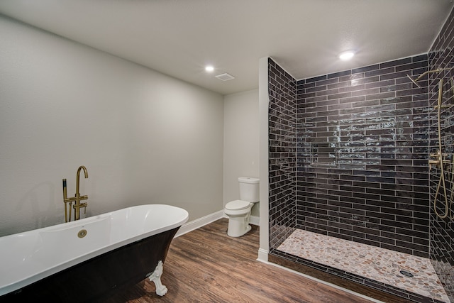 bathroom with wood-type flooring, toilet, and a tub to relax in