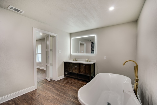 bathroom featuring vanity, a washtub, hardwood / wood-style floors, and a textured ceiling