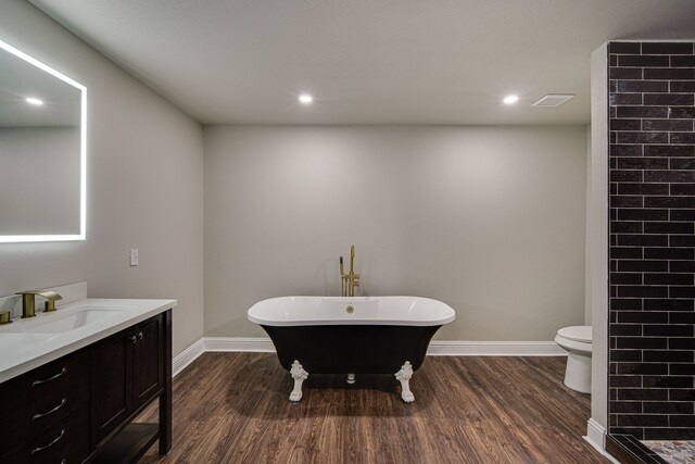 bathroom with wood-type flooring, toilet, vanity, and a bathtub