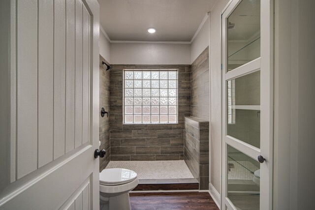 bathroom with hardwood / wood-style floors, tiled shower, toilet, and ornamental molding