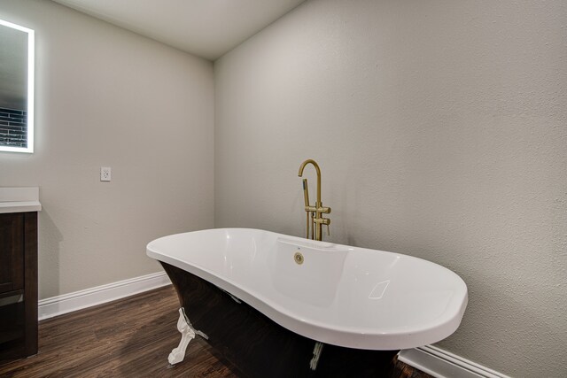 bathroom featuring vanity, a tub, and wood-type flooring