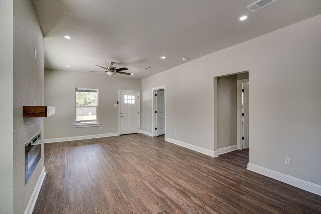 unfurnished living room featuring ceiling fan, dark wood-type flooring, and heating unit