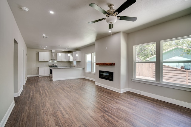 unfurnished living room featuring ceiling fan, sink, and dark hardwood / wood-style flooring