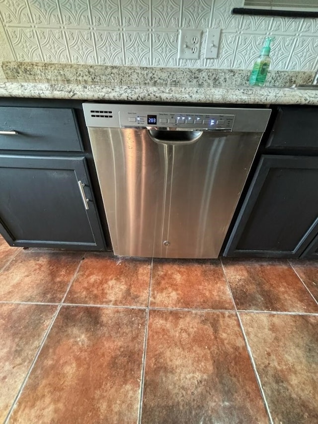 room details featuring dark tile patterned flooring, dishwasher, and light stone counters