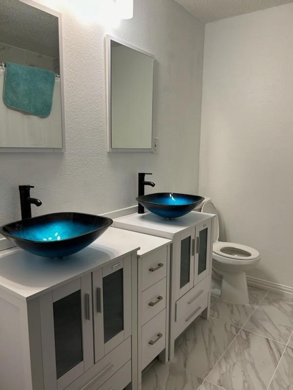 bathroom with double sink vanity, toilet, and tile patterned floors