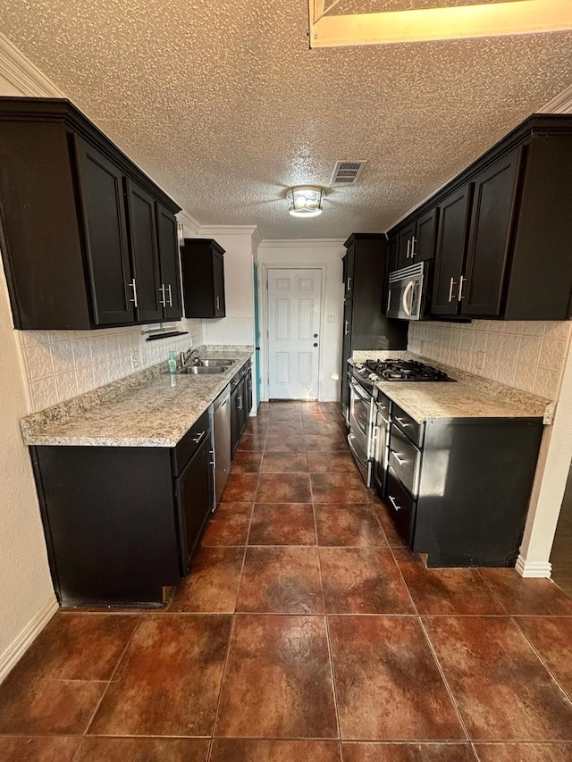 kitchen featuring appliances with stainless steel finishes, backsplash, dark tile patterned flooring, sink, and a textured ceiling