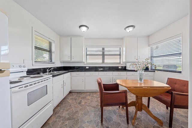 kitchen featuring white cabinets, plenty of natural light, white electric stove, and dark tile patterned floors