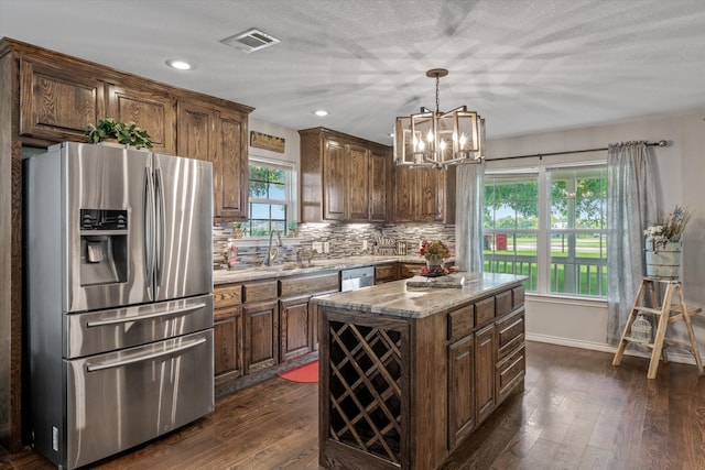 kitchen featuring appliances with stainless steel finishes, decorative backsplash, a wealth of natural light, dark hardwood / wood-style flooring, and a center island