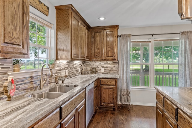 kitchen featuring backsplash, stainless steel dishwasher, dark hardwood / wood-style floors, sink, and light stone countertops