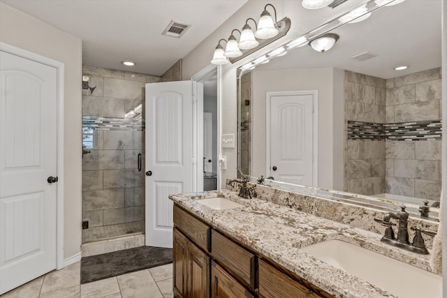 bathroom with tile patterned flooring, tiled shower, and dual bowl vanity