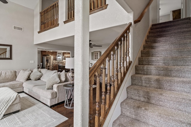 stairs with ceiling fan, hardwood / wood-style floors, and a high ceiling