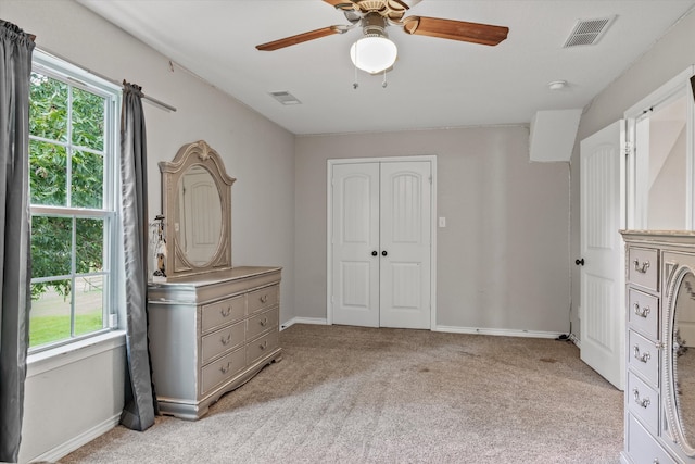 unfurnished bedroom featuring multiple windows, light carpet, a closet, and ceiling fan