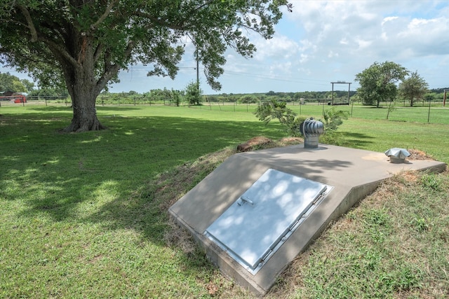 entry to storm shelter featuring a rural view and a lawn