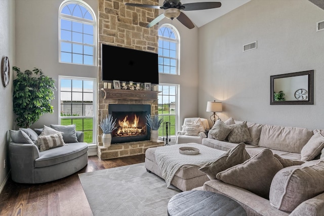 living room with a towering ceiling, dark wood-type flooring, and a fireplace