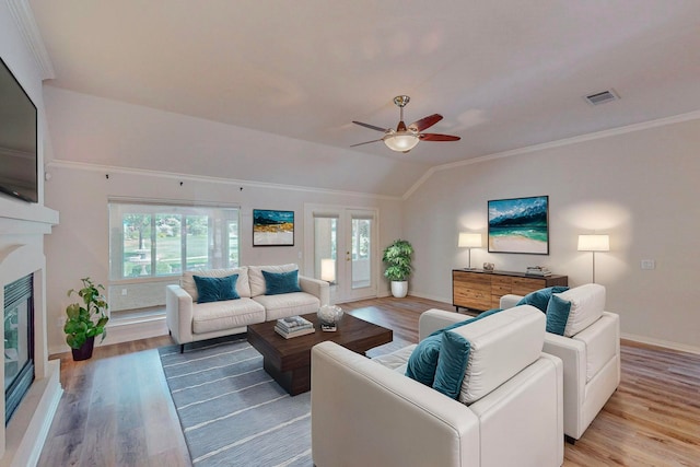 living room with lofted ceiling, ornamental molding, ceiling fan, and light hardwood / wood-style flooring