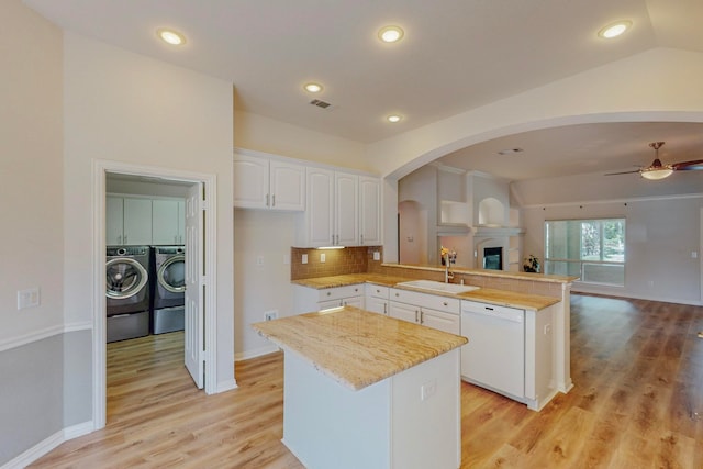 kitchen with ceiling fan, white dishwasher, kitchen peninsula, white cabinetry, and vaulted ceiling