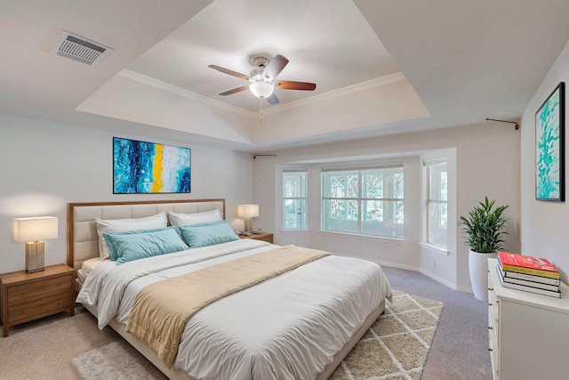 carpeted bedroom with a raised ceiling, crown molding, and ceiling fan