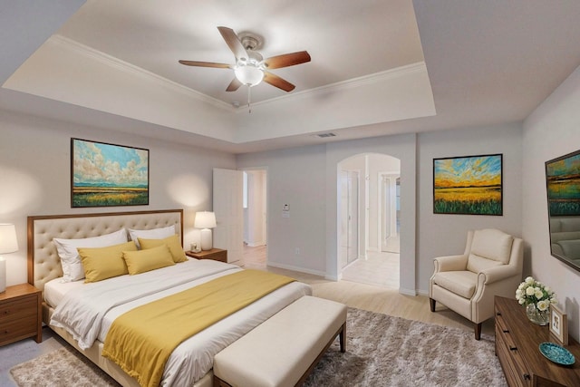 bedroom with a raised ceiling, ornamental molding, ceiling fan, and ensuite bathroom