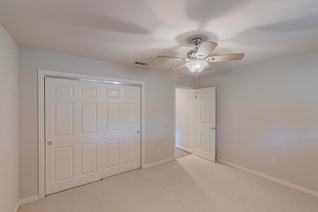 unfurnished bedroom with light carpet, ceiling fan, and a closet