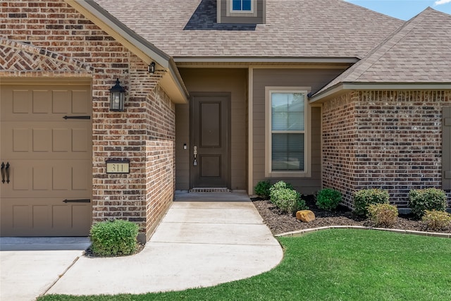 doorway to property with a garage and a yard