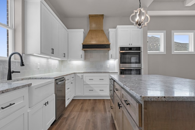 kitchen with appliances with stainless steel finishes, a center island, custom exhaust hood, and white cabinetry