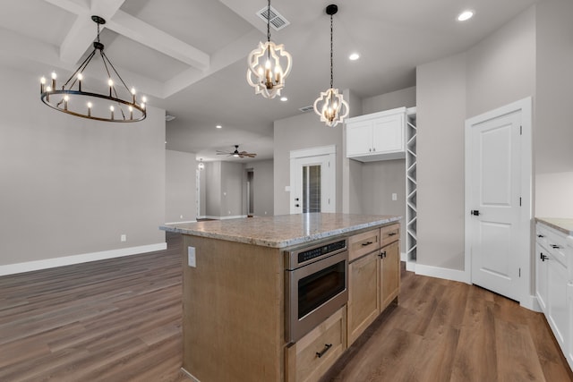 kitchen featuring ceiling fan with notable chandelier, dark hardwood / wood-style flooring, a center island, stainless steel oven, and white cabinets