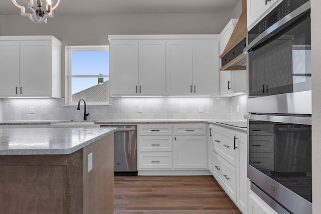 kitchen featuring tasteful backsplash, dark wood-type flooring, stainless steel appliances, a chandelier, and white cabinets