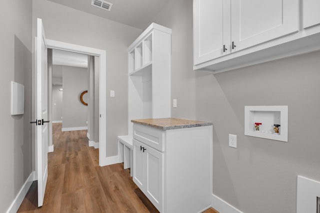 clothes washing area featuring washer hookup, light hardwood / wood-style flooring, and cabinets