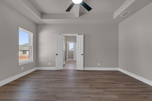 unfurnished room with ceiling fan, hardwood / wood-style floors, and a tray ceiling