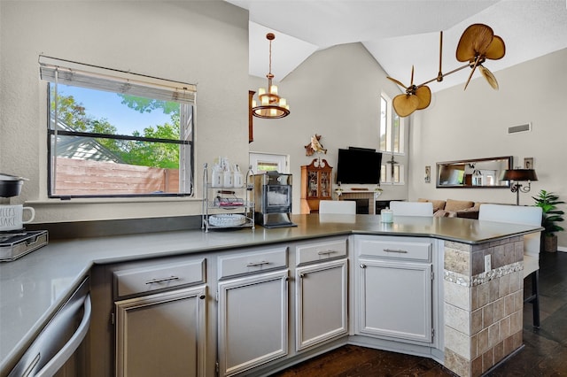 kitchen featuring dark hardwood / wood-style flooring, decorative light fixtures, vaulted ceiling, stainless steel dishwasher, and kitchen peninsula