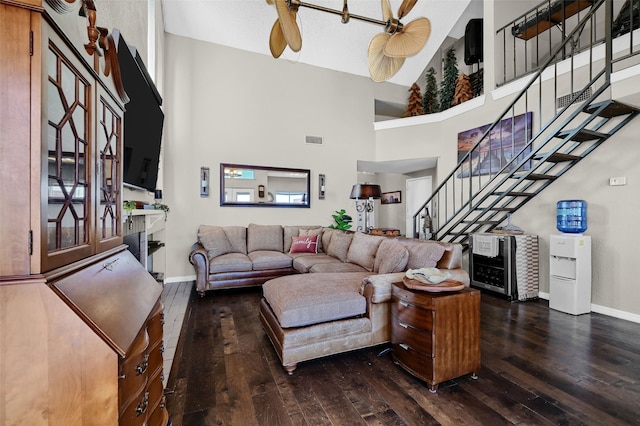 living room with a high ceiling, ceiling fan, and dark hardwood / wood-style flooring