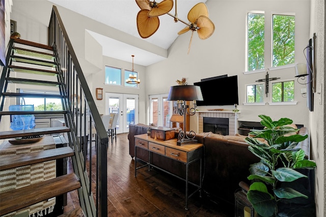 living room with dark hardwood / wood-style floors, high vaulted ceiling, ceiling fan, a brick fireplace, and french doors