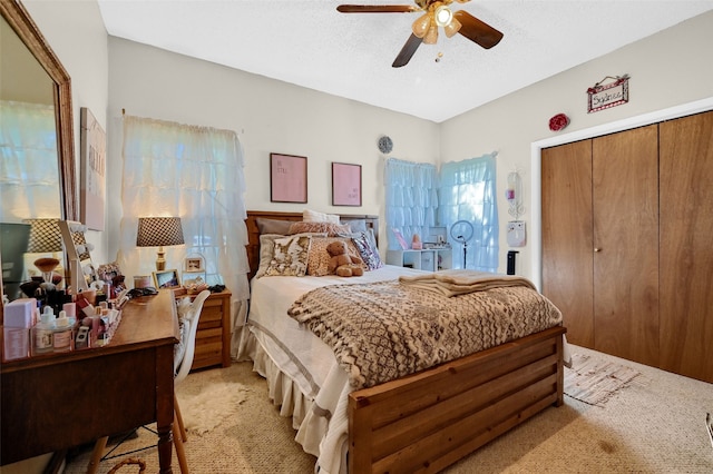 bedroom with light carpet, a textured ceiling, ceiling fan, and a closet