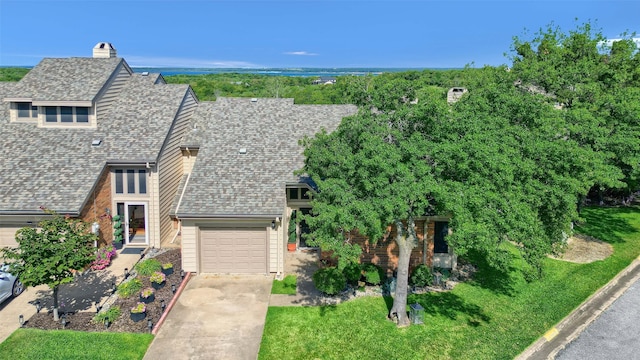view of front of home featuring a chimney, a garage, concrete driveway, and roof with shingles