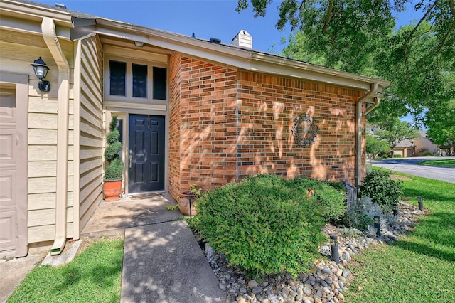 doorway to property with brick siding and a chimney