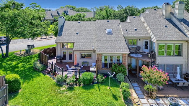 back of property with a chimney, fence, a wooden deck, french doors, and a lawn