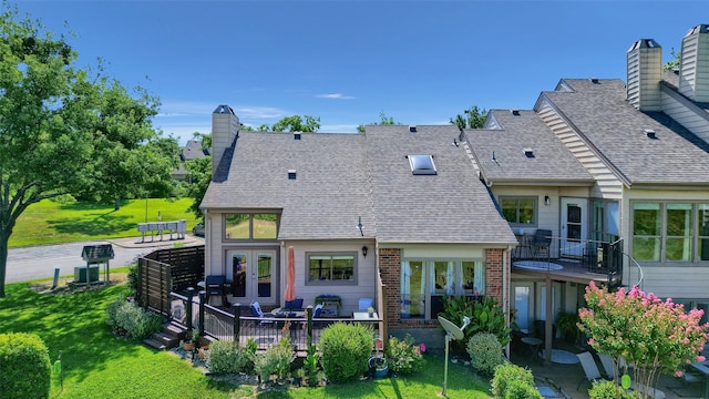 back of property with roof with shingles, french doors, brick siding, a yard, and a chimney