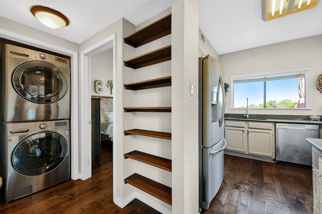 laundry room featuring stacked washer and dryer, sink, and dark wood-type flooring