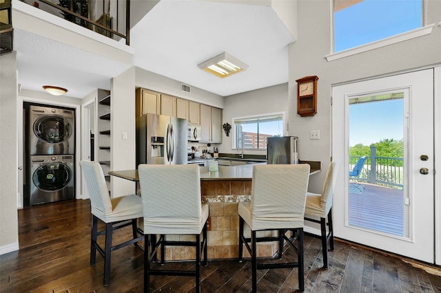 kitchen featuring sink, stainless steel appliances, stacked washer and clothes dryer, dark hardwood / wood-style flooring, and light brown cabinets