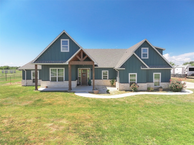 craftsman-style home featuring roof with shingles, a front yard, and stone siding