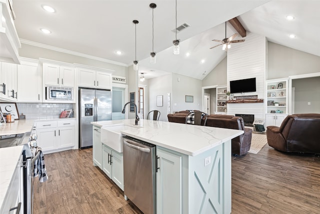 kitchen featuring a kitchen island with sink, a large fireplace, white cabinetry, ceiling fan, and appliances with stainless steel finishes