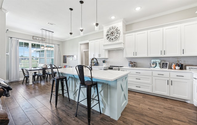 kitchen with white cabinets, decorative light fixtures, dark hardwood / wood-style flooring, a breakfast bar area, and a center island with sink